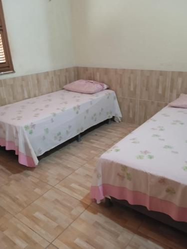 a room with two beds and a wooden floor at Condominio Nina2 in Icapuí