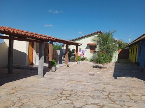 a stone courtyard with a building and a palm tree at Condominio Nina2 in Icapuí