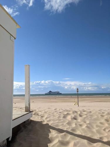 une plage avec un bâtiment sur une plage de sable dans l'établissement Le Sunset, à Sangatte