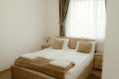 a bedroom with a bed with white sheets and a window at Casa Abiiani in Oradea