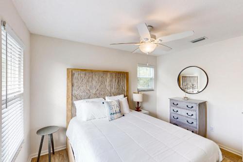Un dormitorio blanco con una cama y un ventilador de techo. en Sea Pine Cottage, en St. George Island