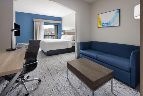 a hotel room with a blue couch and a bed at Holiday Inn Express & Suites Leesburg - Historic District by IHG in Leesburg