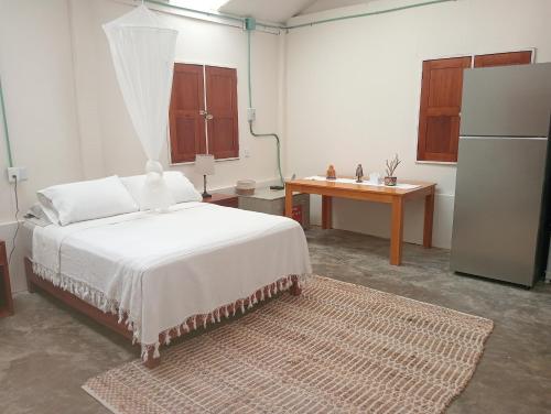 a bedroom with a bed and a desk and a refrigerator at La cabaña del pescador in Tócuaro