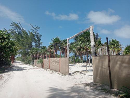 a fence on the side of a beach with palm trees at La cabaña del pescador in Tócuaro