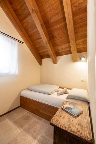 a small bedroom with a bed and a wooden ceiling at Baita Heidi - Villaggio dei Crodini in Crodo