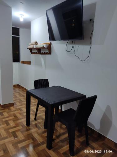 a black table with two chairs and a tv on a wall at D' Barrig in Trujillo