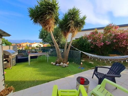 une arrière-cour avec des palmiers, des chaises et un hamac dans l'établissement Country and family villa, à Villeneuve-de-la-Raho