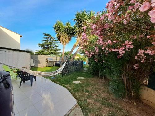 - un jardin avec des fleurs roses et un hamac dans l'établissement Country and family villa, à Villeneuve-de-la-Raho