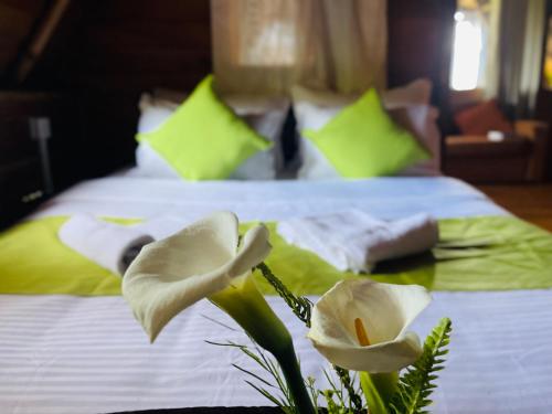 a bed with two white flowers in front of it at The Lake Frost in Nuwara Eliya