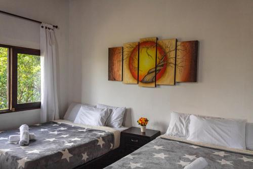 a bedroom with two beds and a painting on the wall at EDYMA Cabaña con JACUZZI in Guatapé