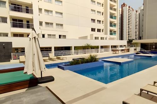 Una piscina con una sombrilla al lado de un edificio. en Bom gosto & Sofisticação Gleba Palhano, en Londrina