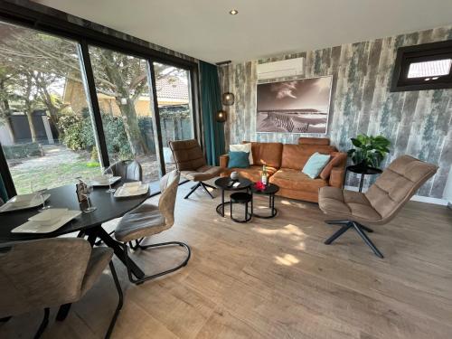 a living room with a couch and a table and chairs at BeachHouse AAN ZEE in Noordwijk aan Zee