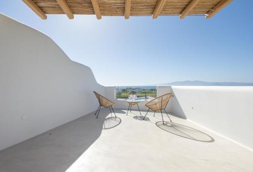 a room with three chairs and a table on a white wall at Kastraki Riviera in Kastraki Naxou