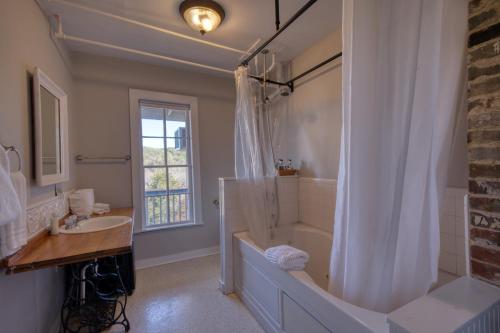 a bathroom with a tub shower and a sink at Downtown Secret Garden Piedmont in Eureka Springs