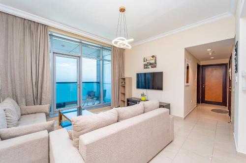 a living room with white furniture and a large window at Beachfront holiday homes with beach,sauna,jacuzzi,cafe,restaurants and more in Ajman