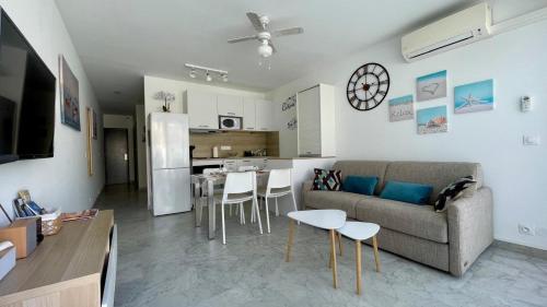 un salon avec un canapé et une table et une cuisine dans l'établissement Appartement Terrasse, centre-ville, 5 min de la plage, à Cavalaire-sur-Mer