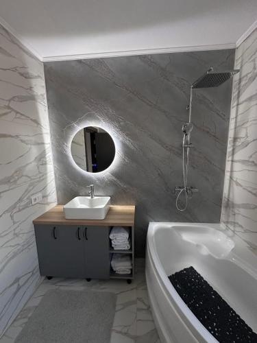 a bathroom with a tub and a sink and a mirror at Apartament Icas in Dej