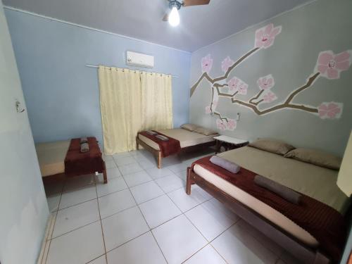 a room with three beds and a tree mural on the wall at Chácara Cantinho dos Sonhos in Chapada dos Guimarães
