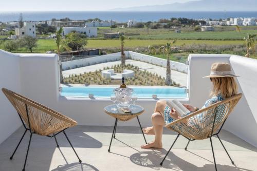 a woman sitting in a chair reading a book on a balcony at Kastraki Riviera in Kastraki Naxou