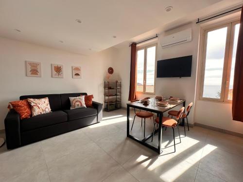 a living room with a black couch and a table at Courts & Coasts few steps from Tennis courts, Country Club and Montecarlo Beach in Roquebrune-Cap-Martin