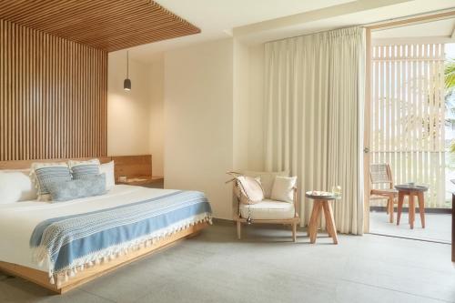 a bedroom with a bed and a chair at Hotel Basalto in Punta Mita
