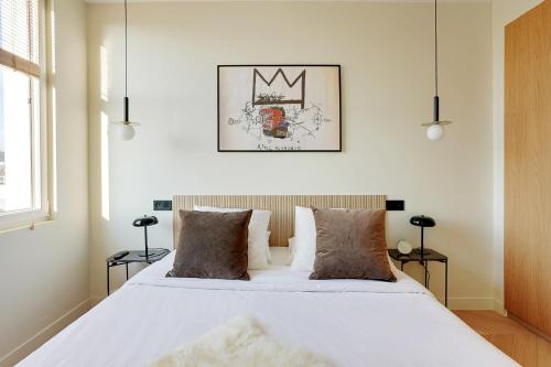 une chambre avec un grand lit blanc avec des oreillers dans l'établissement Riverside Chic Loft, à Boulogne-Billancourt
