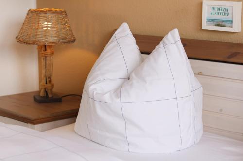 a white pillow sitting on a bed next to a lamp at Strandkojen in Trassenheide