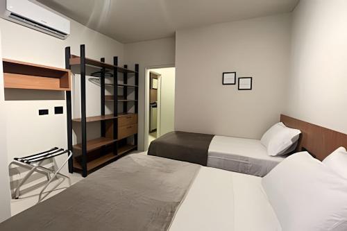 a bedroom with two beds and a chair in it at Flat centro de Londrina - Vista incrível in Londrina