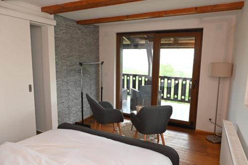 a bedroom with a bed and chairs and a balcony at Forest Heaven Retreat with jakuzz in Čačak