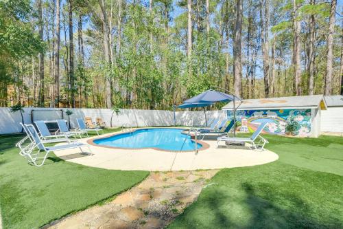 a backyard with a pool with chairs and an umbrella at 7 Mi to Dtwn Durham Home with Hot Tub and Game Room! in Durham
