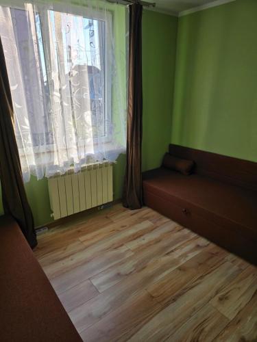 a room with green walls and wooden floors and a window at Kwatera27 in Kleszczele