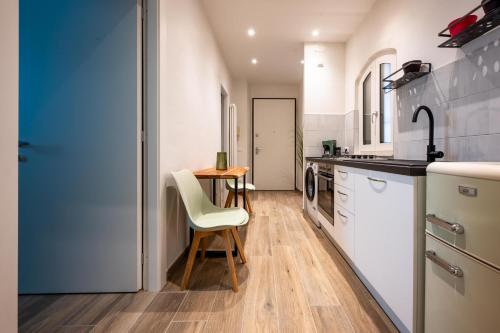 a kitchen with white cabinets and a table and chairs at La Regia Apartment in Cuneo
