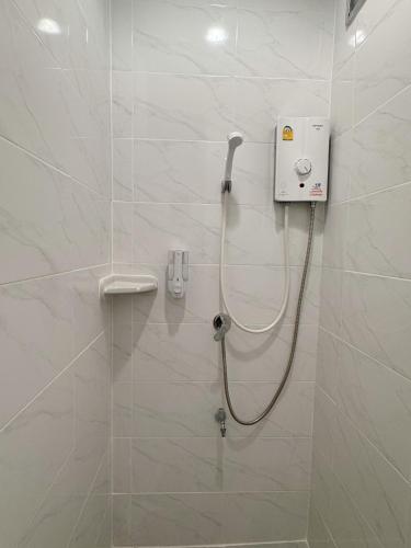 a shower in a bathroom with white tiles at Tokyo Hotel in Nakhon Ratchasima