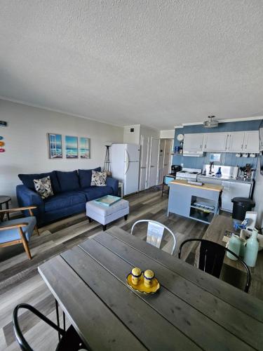 a living room with a blue couch and a table at BEACHSIDE CONDO-WATER AND POOL VIEW Top Floor in Tybee Island