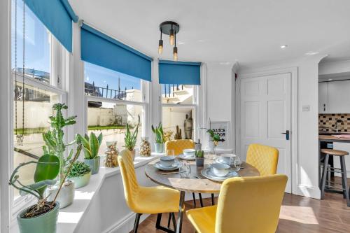 a dining room with a table and yellow chairs at Seaside Gem Apartment By My Getaways in Brighton & Hove