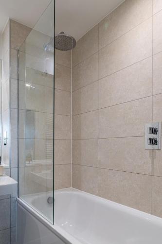 a bathroom with a tub and a glass shower at Manchester City Centre,Picadilly , Skyline View in Manchester