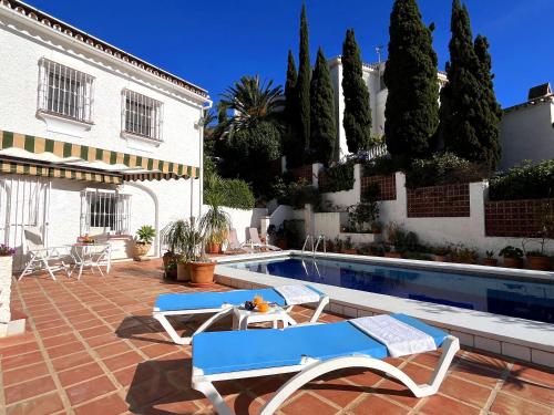 a swimming pool with two chairs and a house at Villa Mara in Caleta De Velez