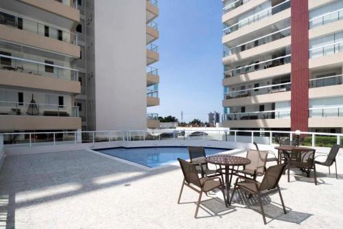 a patio with a table and chairs next to a building at Apto com lazer completo a 500m da Praia da Enseada in Bertioga