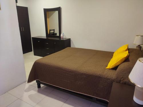 a bedroom with a bed with a yellow pillow and a mirror at Hotel Del Valle, Tecamachalco in Tecamachalco