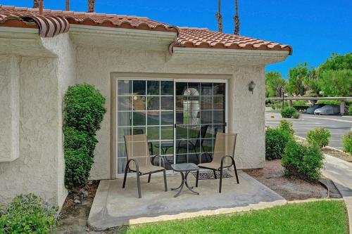 eine Terrasse mit Tisch und Stühlen vor einem Fenster in der Unterkunft Mesquite Desert Bungalow in Palm Springs