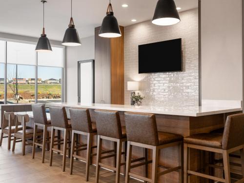 a bar with chairs and a television on a wall at La Quinta Inn and Suites by Wyndham Lincoln in Lincoln