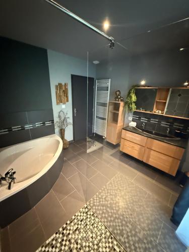 a large bathroom with a tub and a sink at L'écrin de la forêt in Jeanménil