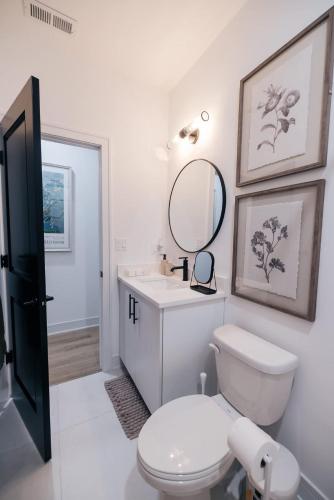 a white bathroom with a toilet and a mirror at Parisian Retreat 6min to Main Quandrangle U of C in Chicago