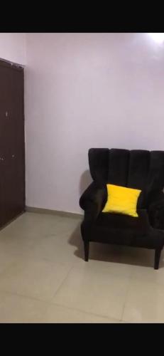 a black couch with a yellow pillow in a room at Allure Guest Inn and Residence Ltd Apartments in Kuramo Island