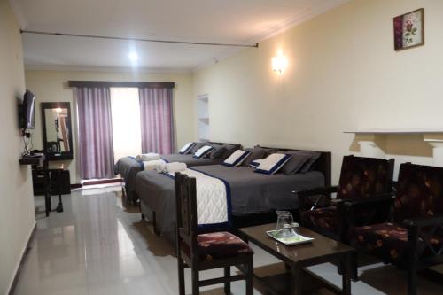 a hotel room with two beds and a table and chairs at Bruton resorts in Kodaikānāl