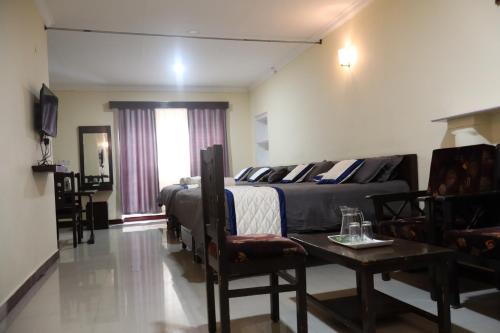 a bedroom with a bed and a table and a couch at Bruton resorts in Kodaikānāl
