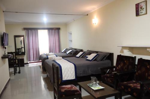 a bedroom with two beds and a living room with chairs at Bruton resorts in Kodaikānāl