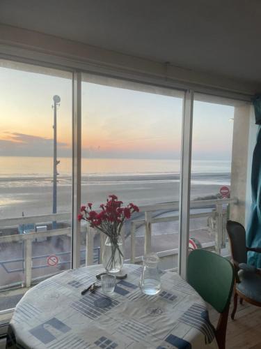 - une table avec un vase de fleurs sur une table avec vue sur l'océan dans l'établissement La Plus Belle vue sur la Mer, à Le Portel