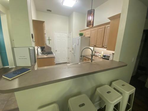 a kitchen with a counter with three stools and a sink at The Lazy Lasso in Edmond