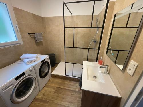 une salle de bain avec une machine à laver et un lavabo dans l'établissement Le N4 des Hauts de SARLAT, Clim Piscine Parking, à Sarlat-la-Canéda